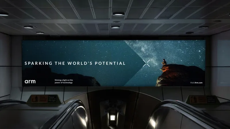 Digital advertising screen in a subway station showing an Arm technology campaign